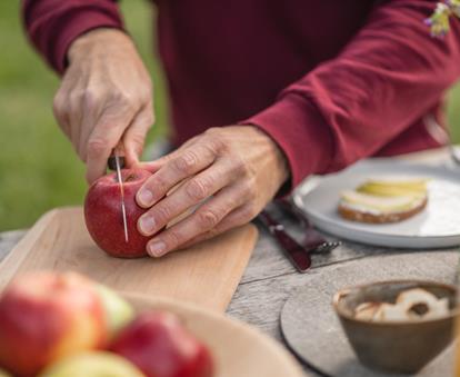 Frisch aufgeschnittener Südtiroler Apfel auf Holzbrett beim Picknick.