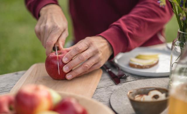 Frisch aufgeschnittener Südtiroler Apfel auf Holzbrett beim Picknick.