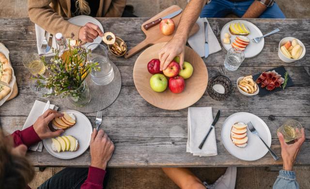 Picknicktisch mit verschiedenen Südtiroler Äpfeln, Apfelsaft, Apfelchips und regionalen Produkten.