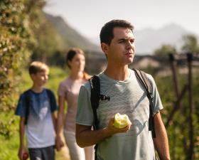 Familie beim Wandern durch Apfelwiesen in Südtirol.