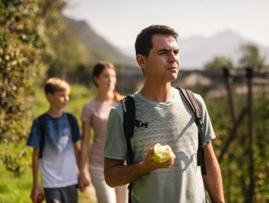 Familie beim Wandern durch Apfelwiesen in Südtirol.